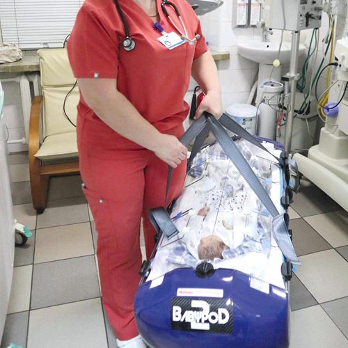 Krankenschwester trägt Transportsystem Babypod an den Gurten